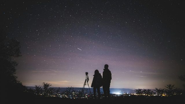 Person standing under a starry night sky with a long-exposure view of the Milky Way