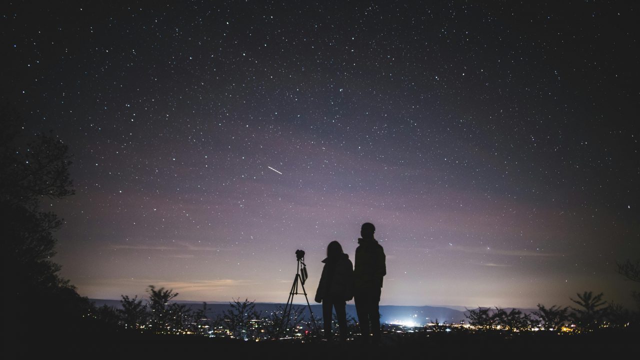 Person standing under a starry night sky with a long-exposure view of the Milky Way